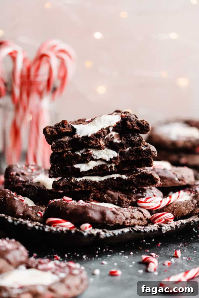 Gooey Peppermint Hot Chocolate Cookies with Marshmallows 11 A straight on view of a stack of the broken open hot cocoa cookies with twinkle lights and candy canes in the background.