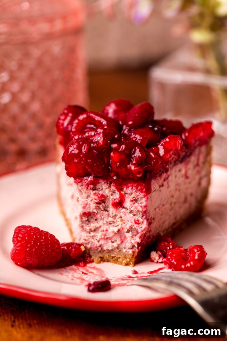 Decadent Raspberry Cheesecake Recipe 9 Bite missing from cheesecake on a plate.
