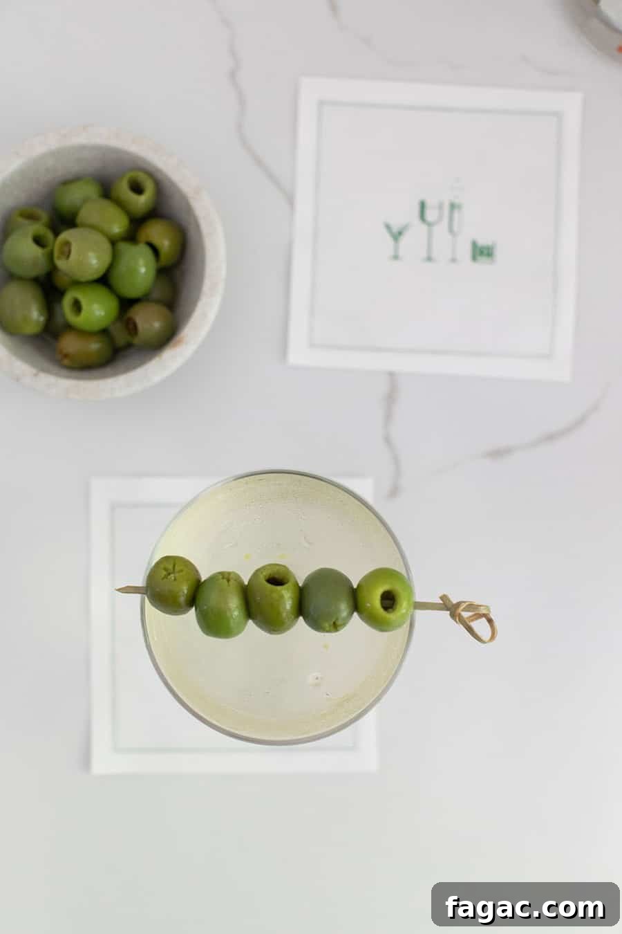 Dirty Martini Recipe: Tips for the Classic Cocktail 5 Dirty martini on a cocktail napkin with a bowl of olives.