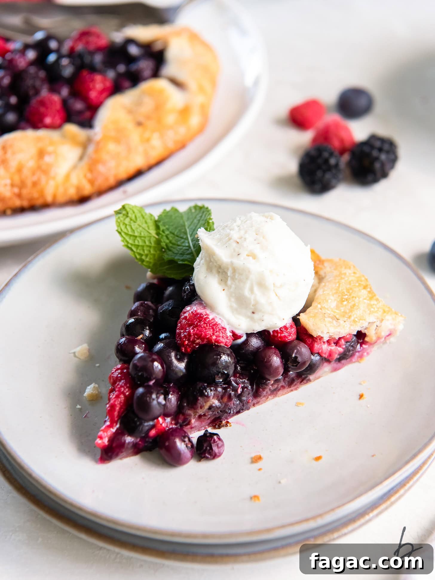 Summer Mixed Berry Galette with Flaky Crust 6 slice of mixed berry galette on a plate with a scoop of vanilla ice cream.