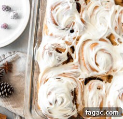 pan of gingerbread cinnamon rolls topped with cream cheese frosting.