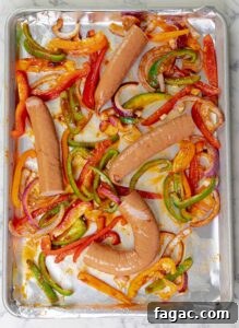 Crispy Sheet Pan Polish Sausage Sandwiches 9 sausages and peppers on baking sheet ready to be cooked