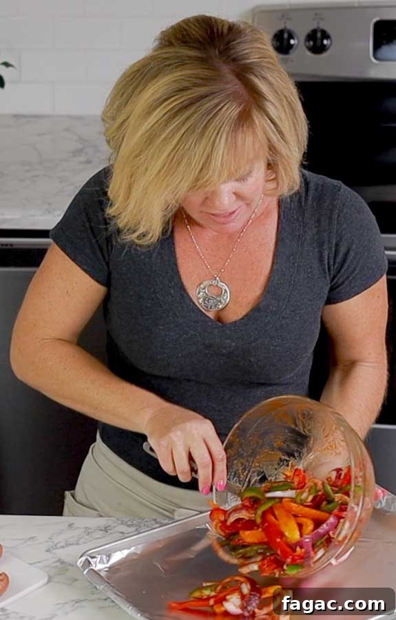 Crispy Sheet Pan Polish Sausage Sandwiches 4 Jennifer pouring peppers on baking sheet