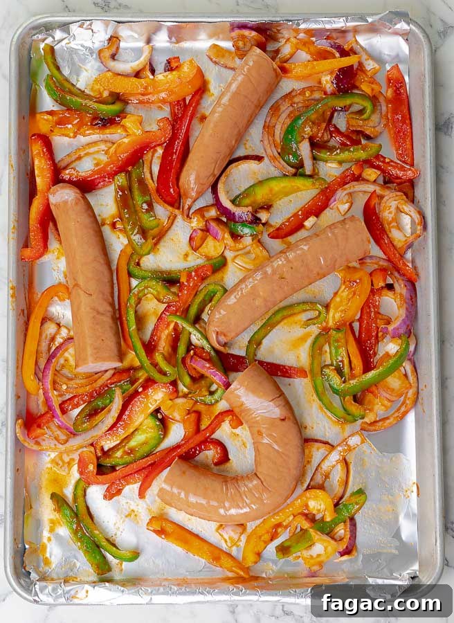 Crispy Sheet Pan Polish Sausage Sandwiches 6 sausages and peppers on baking sheet ready to be cooked